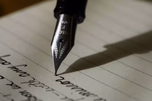 Close-up van vulpen met inscripties JION FR schrijft handgeschreven tekst op gelinieerd papier h2 schrijf jij over jezelf of spreek jij je publiek aan