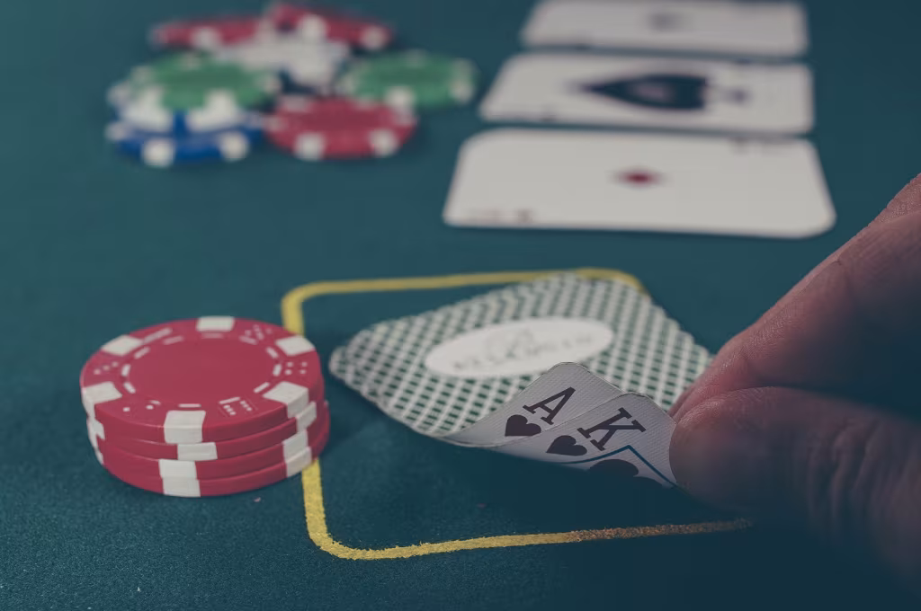 Pokerspel met aas en koning schoppen, rode fiches en inzetvlak op groene tafel, h2 titel over professioneel pokeraar